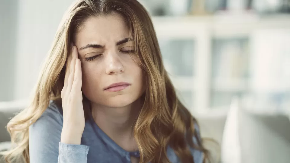 Young woman with headache in home interior Vertigo Chiropractor